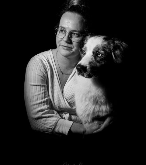 Portrait en noir et blanc de Justine, fondatrice de Éduc au Poilpret, et Sky, son Berger Australien – Un lien unique entre humain et chien